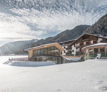 Hotel Vierbrunnenhof © Manuel Kottersteger Hotel Vier Brunnenhof im verschneiten Tal vor bewaldetem Berg