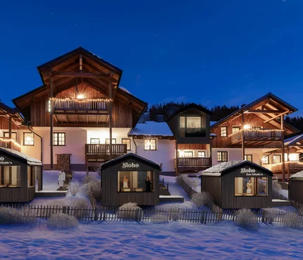 SLOHO Mountain Holiday Apartments © Cathrine Stukhard Illuminated wooden chalets in a snow-covered setting at dusk