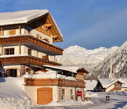 Penserhof | Alpine Hotel & Restaurant © Cavosi Schneebedecktes Chalet vor Berglandschaft in klarem Winterwetter