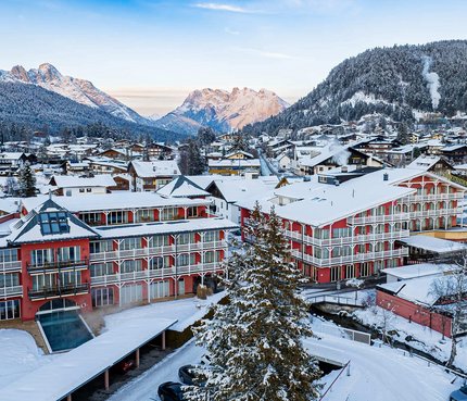 Hotel Eden Winterliches Dorf mit verschneiten Häusern und Bergen im Hintergrund
