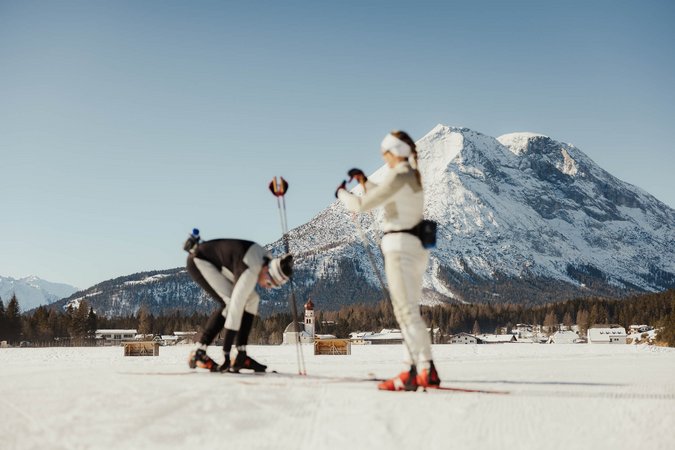 Langlauf Urlaub © Alex Moling Zwei Langläufer auf verschneiter Loipe vor Alpenpanorama