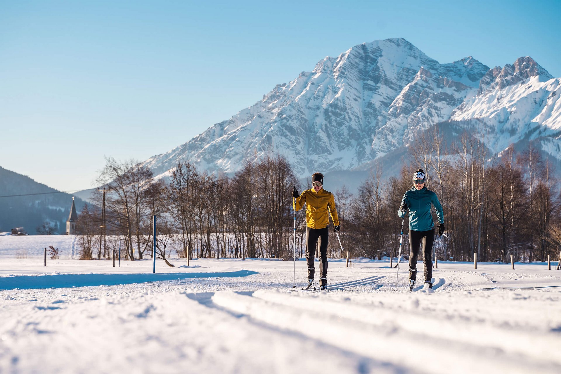 Cross Country Ski Holidays © Michael Geißler Two cross-country skiers on snow with mountain in background on sunny day