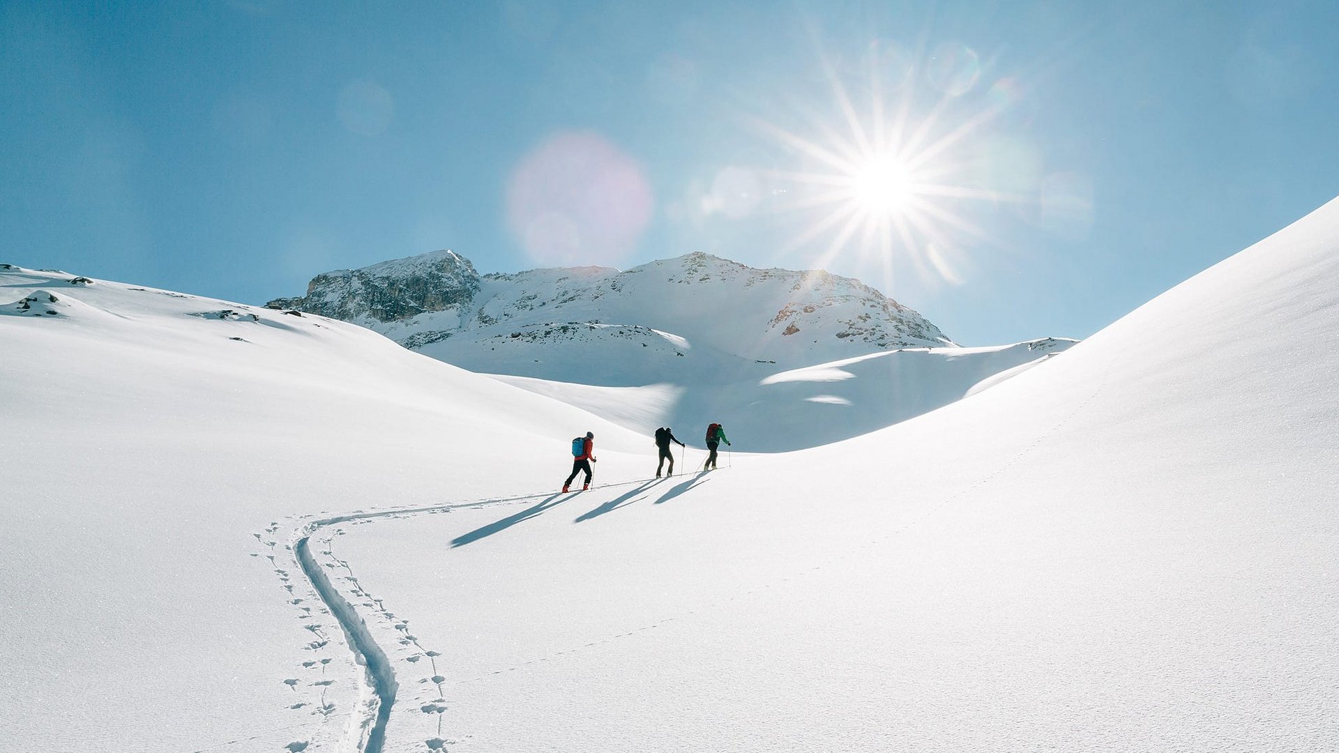 Langlauf Urlaub © Tourismusverein Passeiertal - Benjamin Pfitscher Drei Personen wandern im Schnee bei strahlendem Sonnenschein in den Bergen