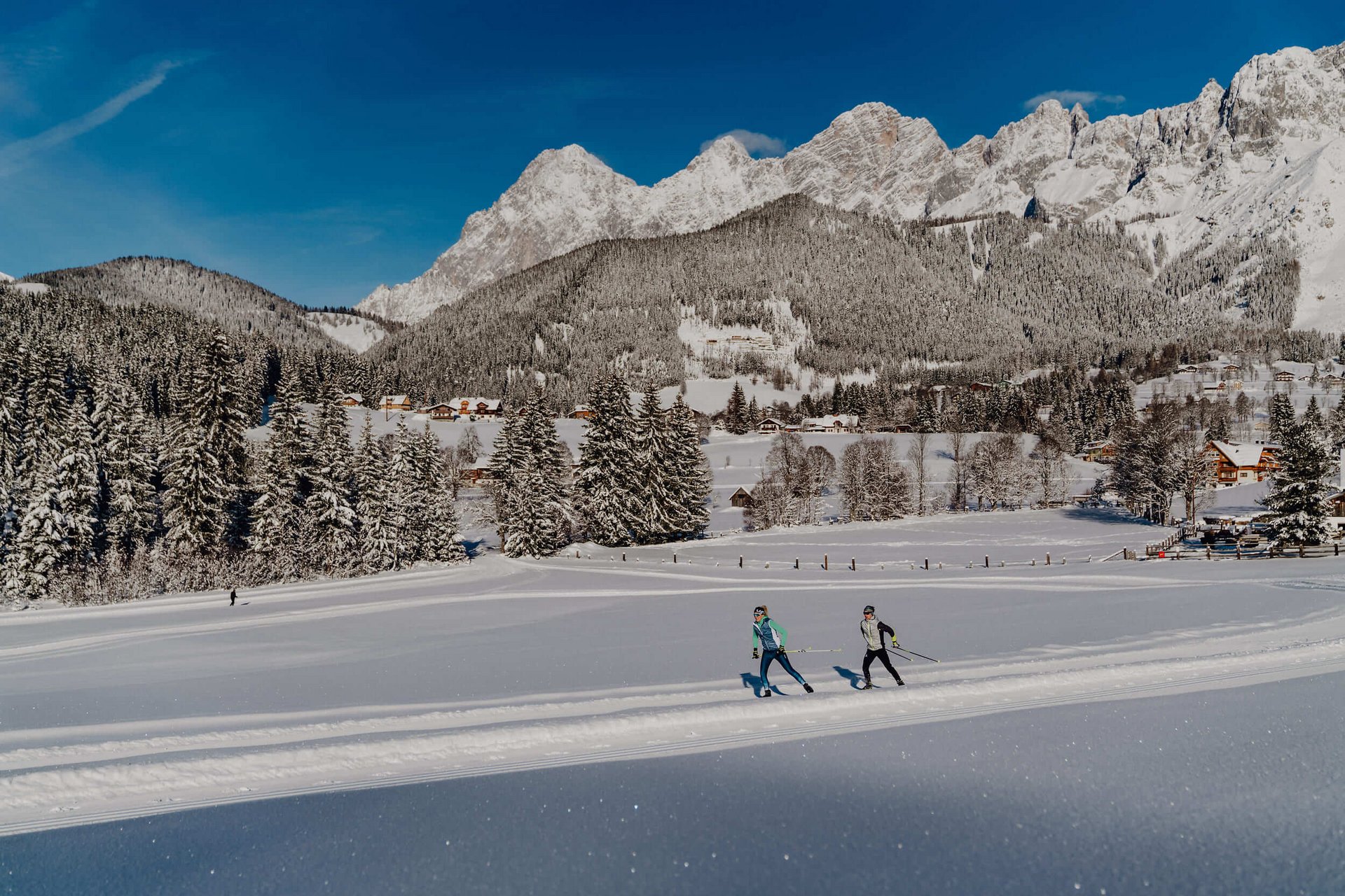 Langlauf Urlaub © TVB Schladming Dachstein - Christine Höflehner Skifahrer auf verschneiter Loipe vor Bergkulisse und Wald