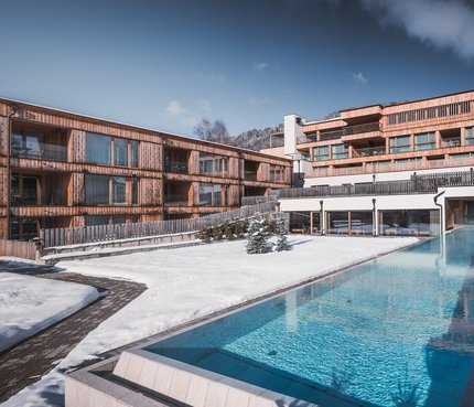 Eco-Aparthotel HIRBEN Naturlaub © Manuel Kottersteger Moderne Holzhäuser mit Pool im winterlichen Schnee
