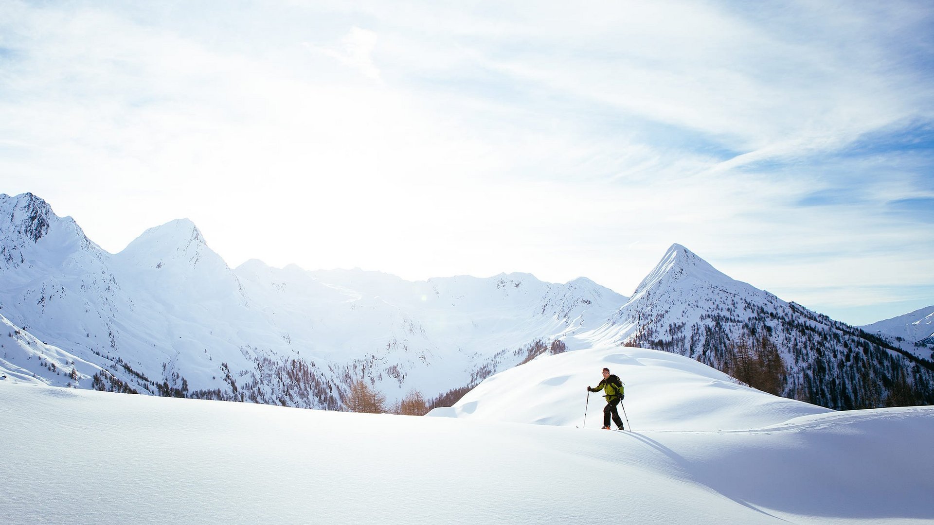 Langlauf Urlaub © Tourismusverein Passeiertal - Benjamin Pfitscher Skifahrer wandert auf schneebedecktem Berg im Sonnenlicht