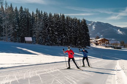 Fis Weltcup Nordische Kombination © TVB Schladming Dachstein - Christine Höflehner Zwei Langläufer auf verschneiter Loipe vor Wald und Bergen