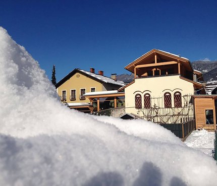Bierhotel Loncium © Bierhotel Loncium Schneebedeckte Häuser unter klarem blauem Himmel in den Bergen