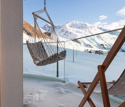 Hotel Langtaufererhof © Anneliese Kompatscher Terrasse mit Hängesessel und Liegestuhl vor schneebedeckten Bergen