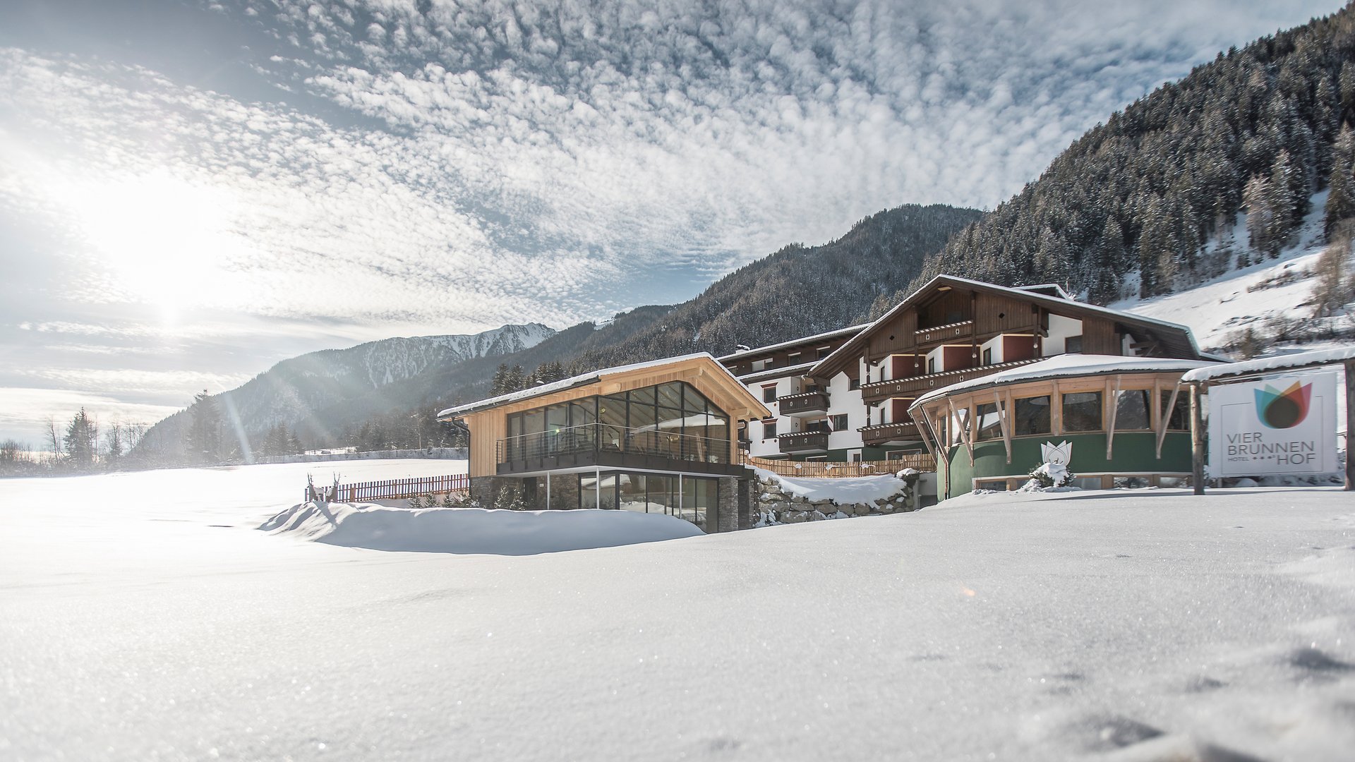 Hotel Vierbrunnenhof ***S © Manuel Kottersteger Hotel Vier Brunnenhof im verschneiten Tal vor bewaldetem Berg