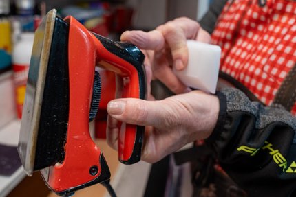Das Kleine Ski-Wachsen 1x1 © Edith Danzer Person hält ein Rot- und Schwarze Bügeleisen und ein weißes Werkzeug in der Hand