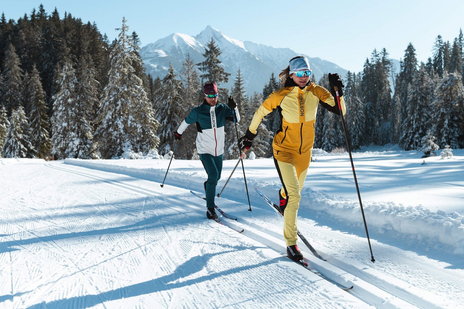 Langlauf Urlaub © Region Seefeld - Moritz Klee Zwei Langläufer in bunter Ausrüstung auf verschneiter Loipe vor Bergen
