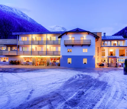 Hotel Bergkristall © Lebesmühlbacher Beleuchtetes Hotel vor schneebedeckten Bergen am Abend