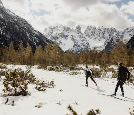 50. Volkslanglauf Toblach-Cortina © Alex Moling Zwei Langläufer im verschneiten Gebirgstal vor schneebedeckten Bergen