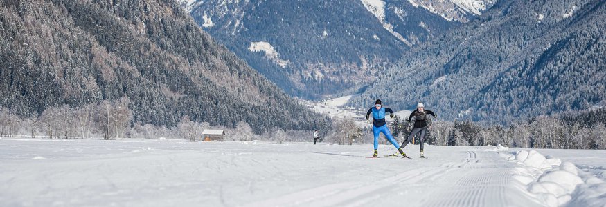 Dolomitenregion Kronplatz © Harald Wisthaler Skilangläufer auf verschneiter Strecke vor Bergkulisse in winterlicher Landschaft