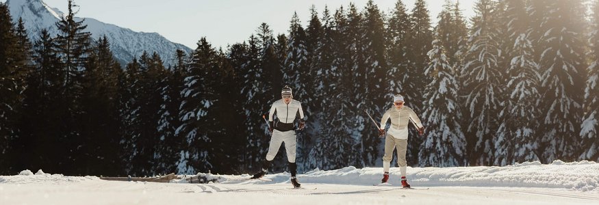 All Inclusive Hotel zum Gourmet **** © Alex Moling Zwei Skilangläufer auf verschneiter Strecke vor Wald und Bergkulisse