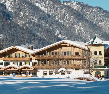 Landhotel Strasserwirt © Reinhold Glaser Schneebedecktes altes Holzhaus vor bewaldetem Berg im Winter