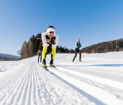 Lungauer Langlauftage © Salzburger Lungau Drei Personen beim Langlaufen auf präparierter Schneestrecke bei Sonnenschein