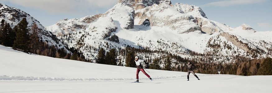 Apparthotel Germania *** © Alex Moling Zwei Langläufer in verschneiter Berglandschaft vor sonnigen Bergen