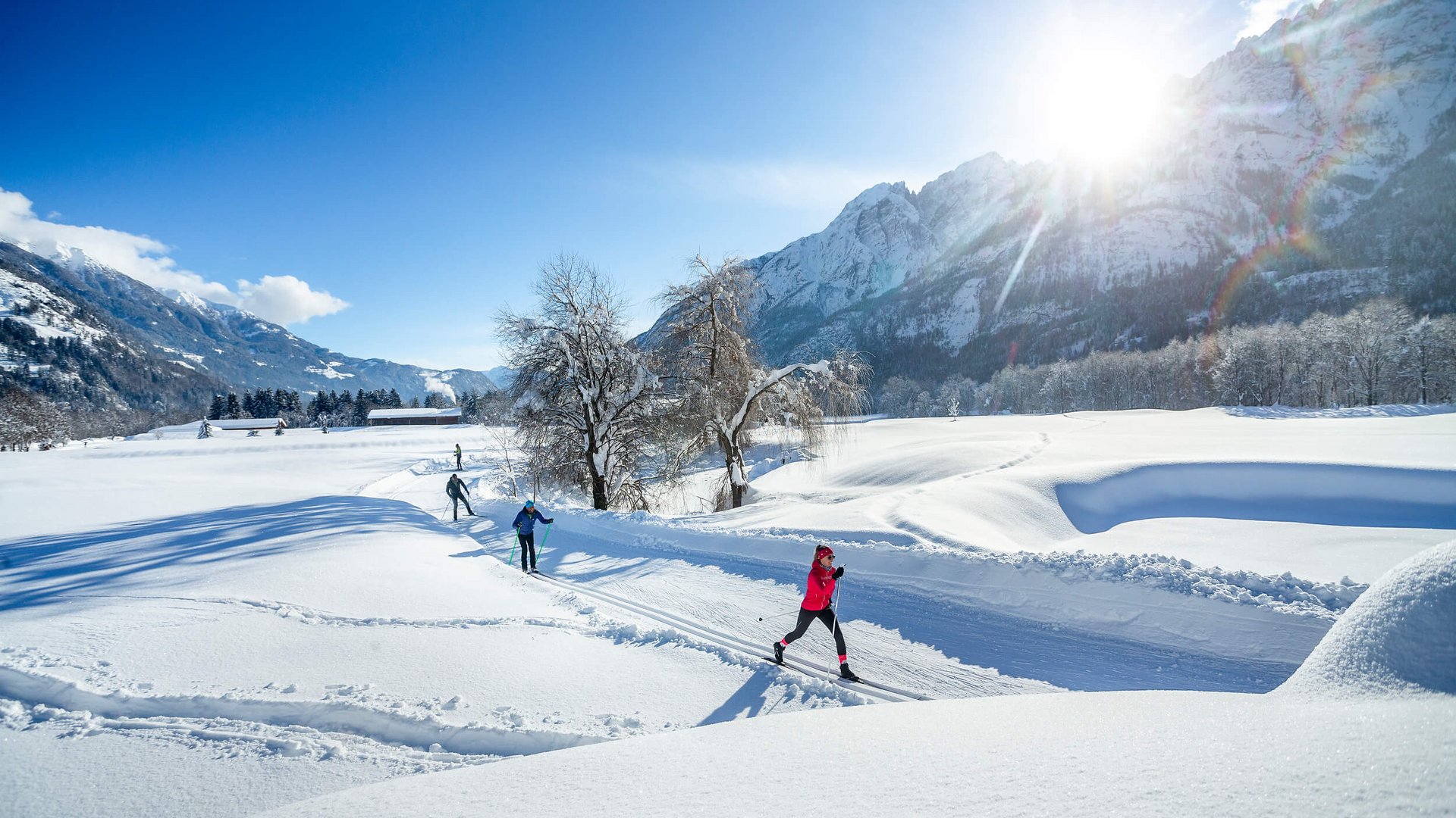 Langlauf Urlaub in Osttirol © Martin Lugger Langläufer im sonnigen, verschneiten Bergtal vor schneebedeckten Bergen