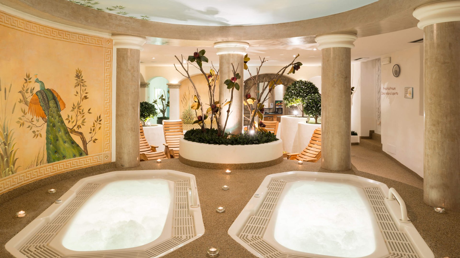 Apparthotel Germania *** © Apparthotel Germania GmbH Innenraum mit zwei Whirlpoolbecken, Säulen und Wandmalerei eines Pfaues