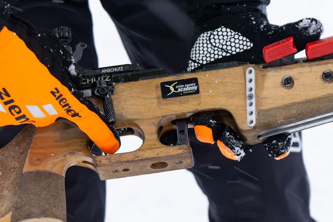 Langlauf Urlaub © Region Seefeld Person hält Biathlon-Gewehr mit orangenen Handschuhen im Schnee