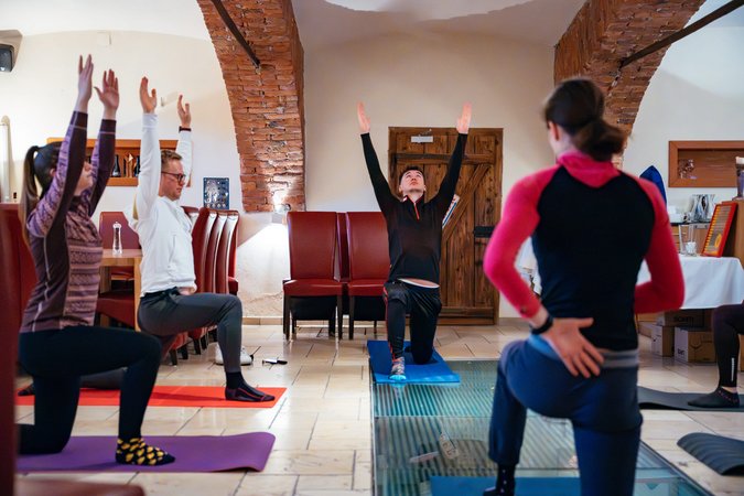 Trainieren im Bierhotel Loncium © Sportalpen Gruppe übt Yoga in einem Raum mit Backsteinbögen und Matten auf dem Boden