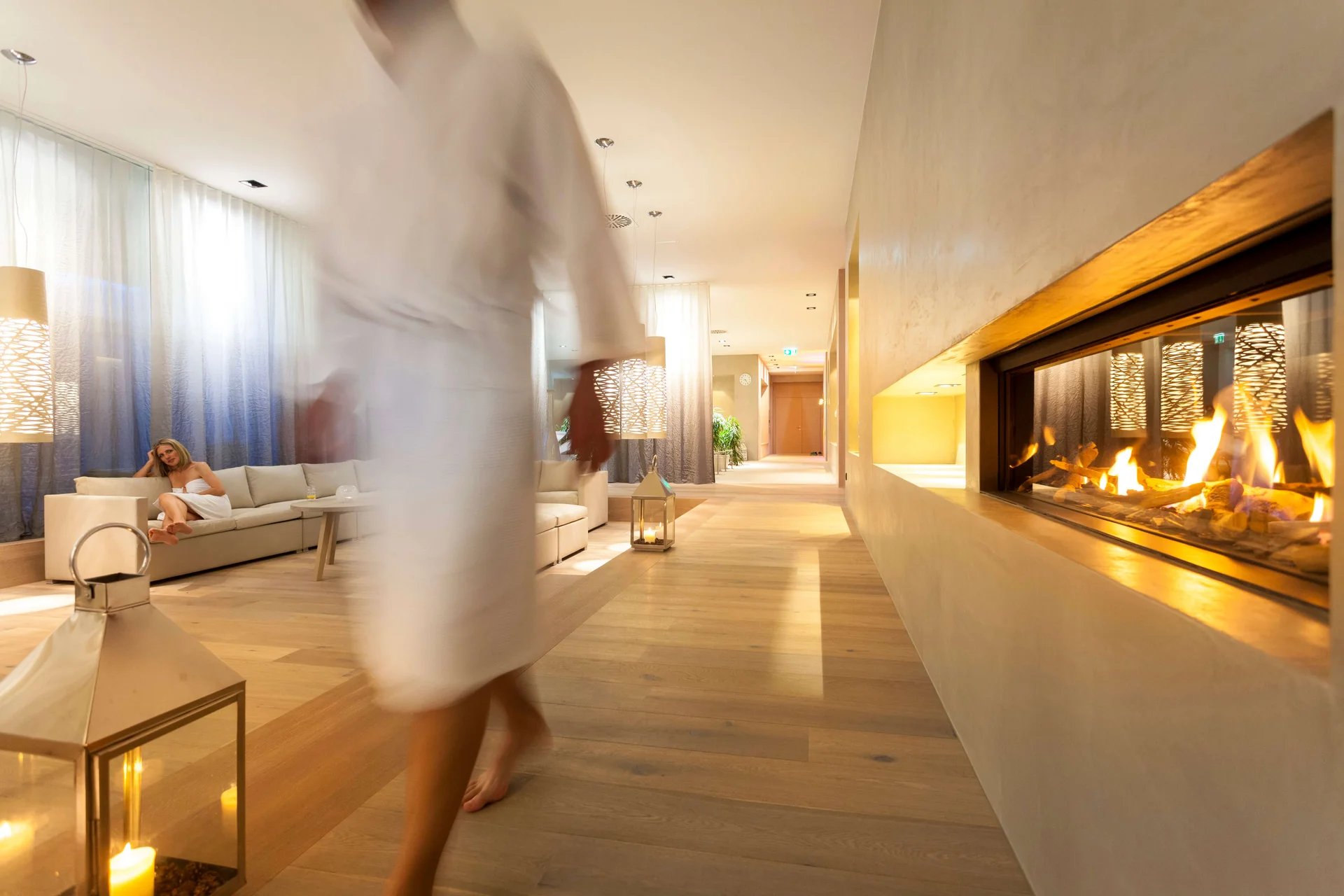 Langlauf Urlaub © Martin Lugger Gemütliche Hotellounge mit Kamin, Sofa und einer Frau im Vordergrund