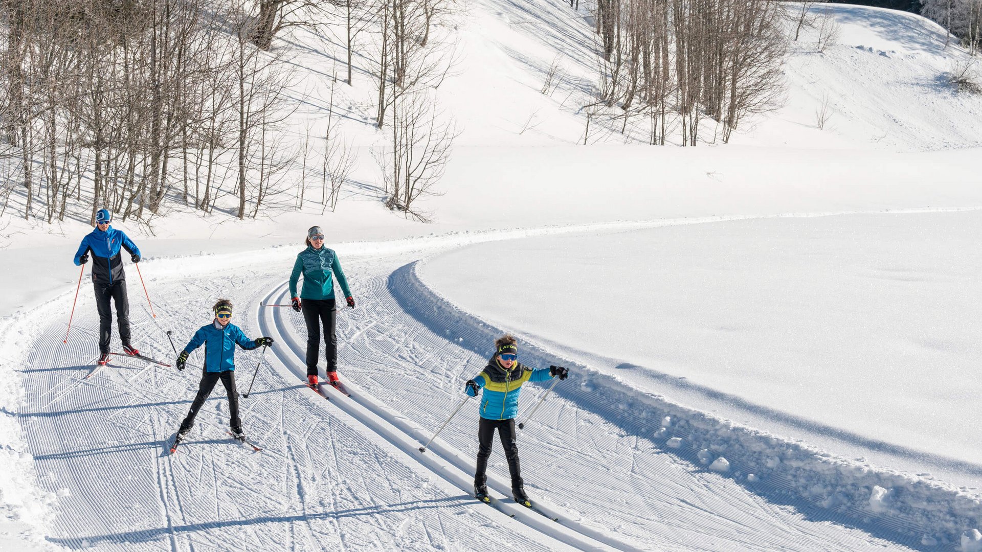 Langlauf Urlaub in Filzmoos © Lorenz Masser - Filzmoos Tourismus Familie beim Langlauf auf verschneiter Loipe im sonnigen Winterwald