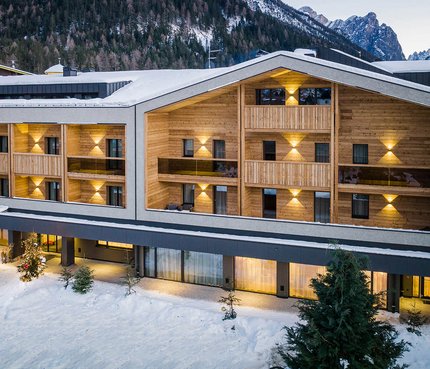 Hotel Laurin's © Harald Wisthaler Modernes Hotel in verschneiter Berglandschaft mit beleuchteten Balkonen