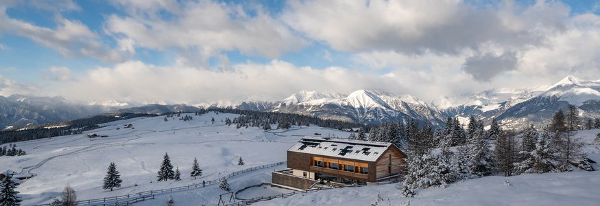 Gitschberg-Jochtal © Jonas Eisenstecken Holzhaus in verschneiter Berglandschaft mit bewölktem Himmel