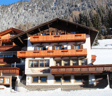 Pension Widmann © Petra und Jürgen Widmann Alpenhaus mit verschneiten Bäumen im Hintergrund unter blauem Himmel