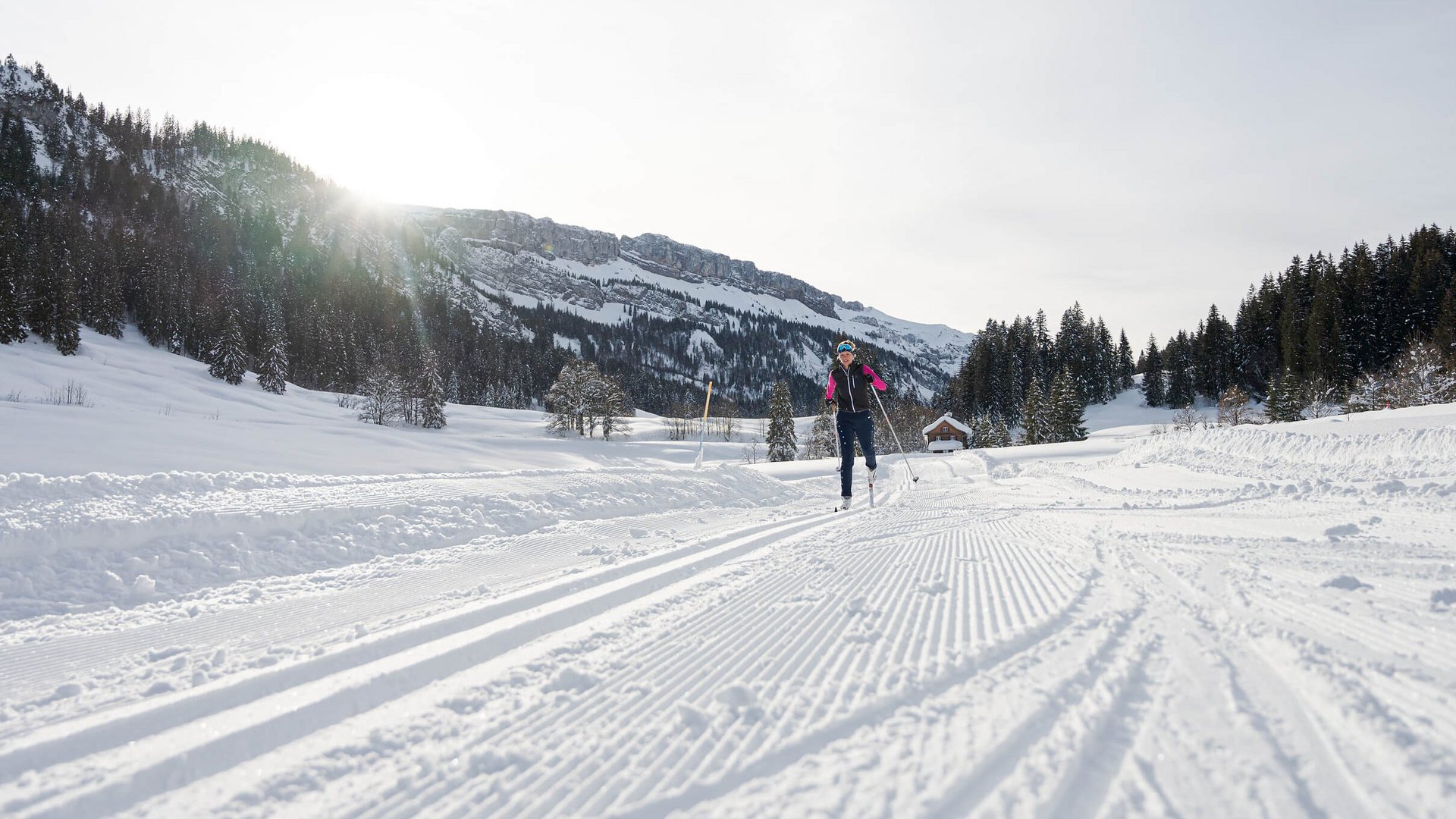 Winterurlaub in Bayern © Frithjof Kjer Person beim Skilanglauf auf verschneiter Loipe vor Bergkulisse bei Sonnenschein