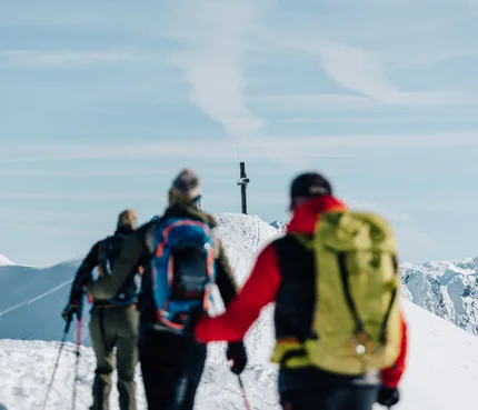 Skitouren-Kurse im Passeiertal © Tourismusverein Passeiertal - Benjamin Pfitscher Wanderer auf schneebedecktem Bergweg im Winter, Gipfelkreuz sichtbar