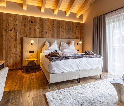 Paradise Lodge © Simone Imperioli Gemütliches Hotelzimmer mit Holzwand, Doppelbett und großem Fenster