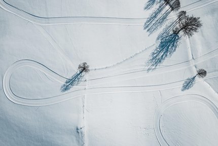 Der Nordic Park in Saalfelden-Leogang © Michael Geißler Luftaufnahme von verschneiten Feldern mit vereinzelten Bäumen und Spuren von Fahrzeugen