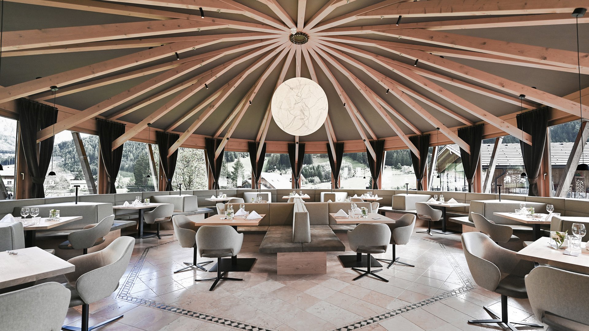 Hotel Vierbrunnenhof ***S © Justina Zdanoviciute Moderner runder Speisesaal mit großen Fenstern und Holzbalkendecke