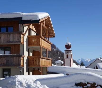 Zangerlehof © Heinrich Moriggl Schneebedecktes Holzalmenhaus und Uhrturm in einem Alpenort