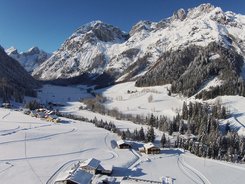 Tennengau Snow-covered alpine landscape with houses and pine trees under clear sky