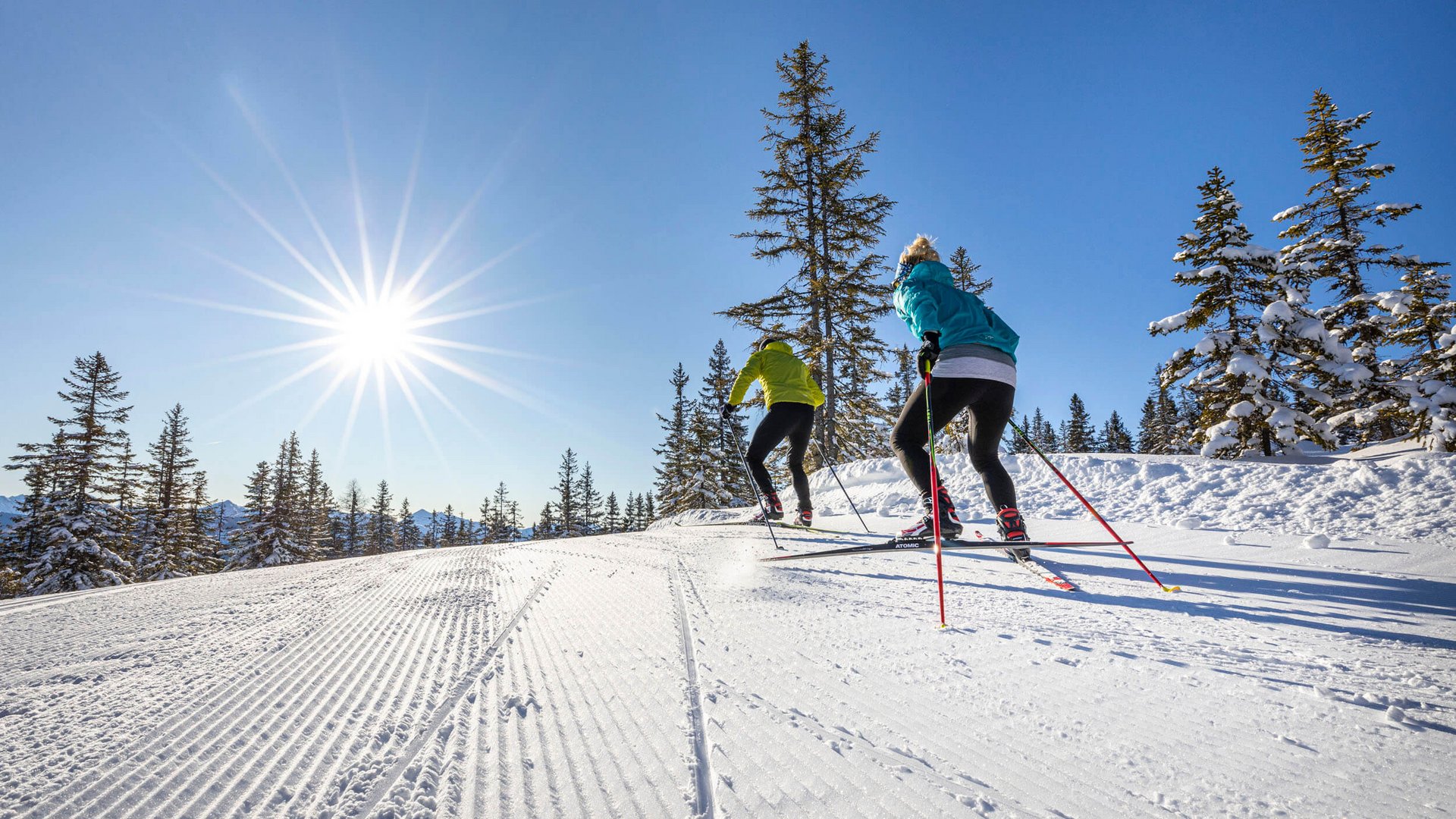 Winter holiday in SalzburgerLand © Christian Fischbacher - Filzmoos Tourismus Two cross-country skiers in sunlight on a snowy trail with trees