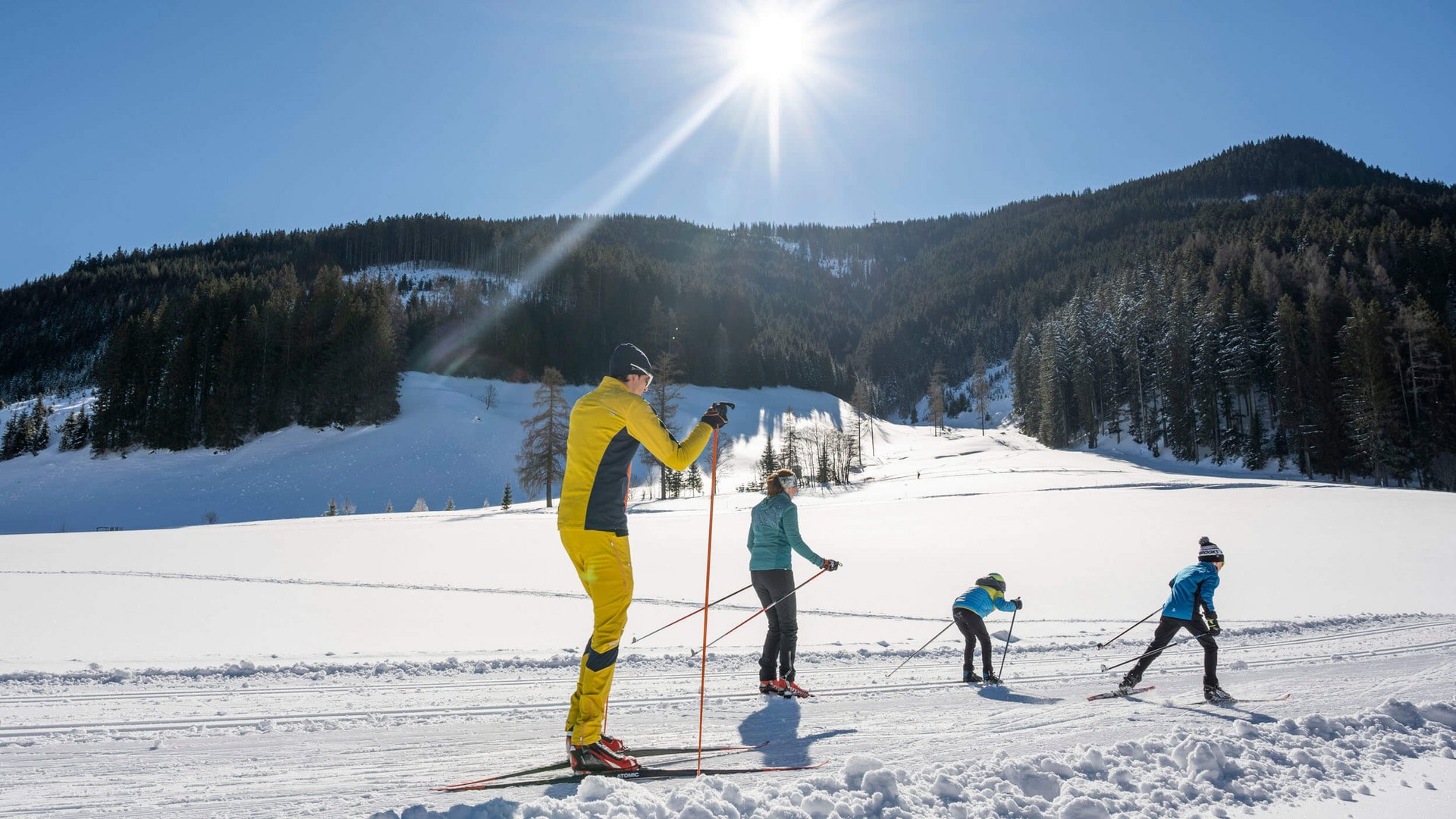 Langlauf Urlaub in Filzmoos © Lorenz Masser - Filzmoos Tourismus Familie beim Langlaufen auf verschneiter Berglandschaft bei Sonnenschein