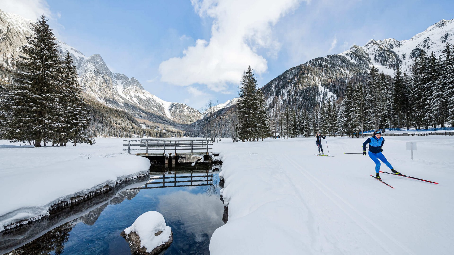 Langlauf Urlaub in der Dolomitenregion Kronplatz © Harald Wisthaler Langläufer unterwegs auf verschneiter Winterlandschaft mit Bergen und Wald