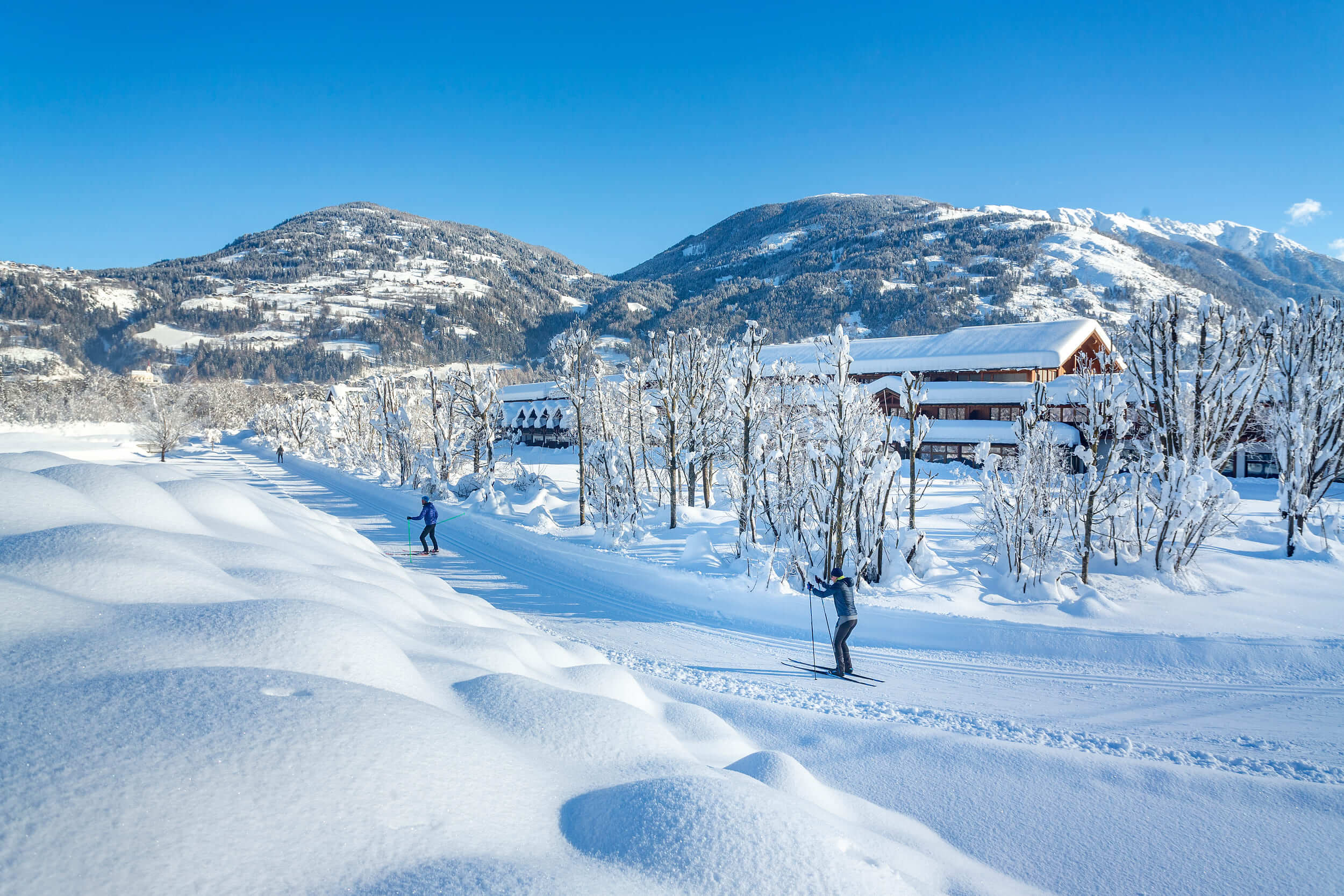 Osttirol © Martin Lugger Menschen beim Langlaufen auf schneebedecktem Weg vor Bergkulisse